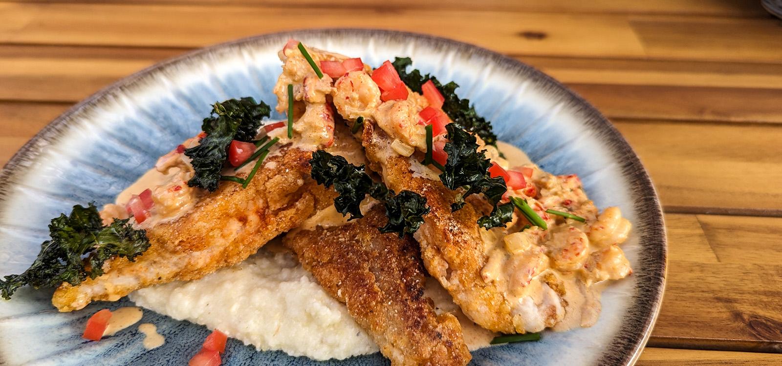 Pan Fried Catfish and GritsTopped with Crawfish in Cream Sauce and Kale Chips